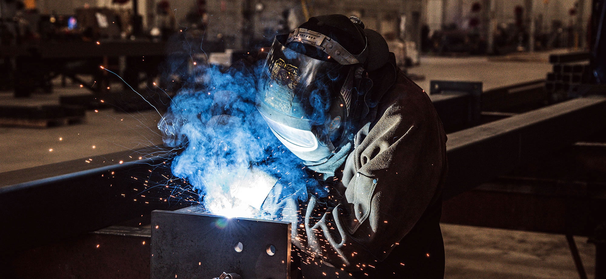 Man welding pipe with protective mask on