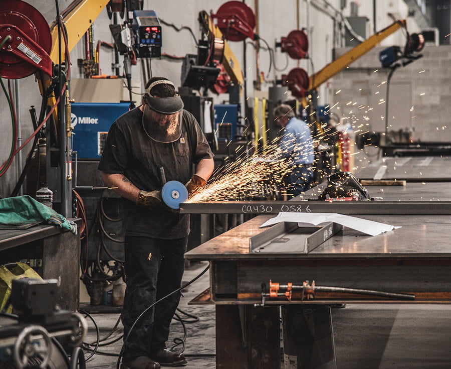 man grinding steel beam with protective mask on