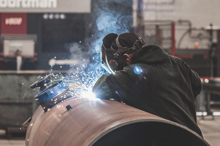 man welding pipe with protective mask on